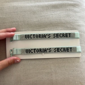 Mintgröna bh band Victoria's Secret - Två mintgröna bh band från Victoria's Secret med glittriga stenar och tydlig logga i svart.  har justerbart band i satinliknande material och är perfekta för att ge din outfit lite extra bling.