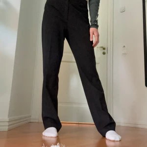 Svarta kostymbyxor från Joy, stl 38 - Svarta kostymbyxor från Joy i storlek 38. Byxorna har hög midja, raka ben och klassisk passform.