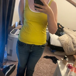 Gul ribbad linnetopp - Snygg gul ribbad linnetopp.  Modellen är tight och ärmlös, perfekt för dig som gillar färg och vill ha en enkel men fräsch look. Passar till jeans eller shorts och är superbekväm under varma dagar.