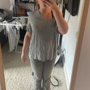 Grå loose t-shirt med v-ringning - Säljer en grå t-shirt med v-ringning och loose passform. Tröjan har korta ärmar och är tillverkad i ett mjukt bomullstyg. Den har en avslappnad look och kan bäras offshoulder för en chill vibe.