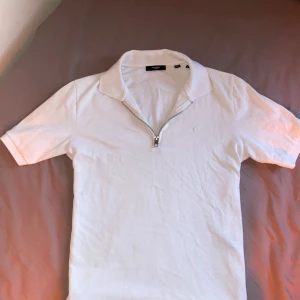 Vit pikétröja med dragkedja Jack & Jones - Vit pikétröja från Jack & Jones med krage och half zip framtill. Tröjan har korta ärmar och är väldigt stilren. Skriv dm om intresse.