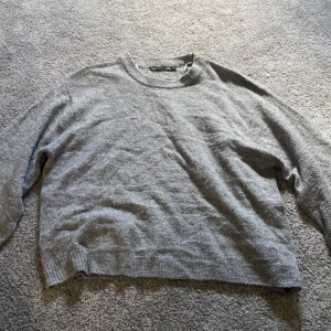 Grå stickad tröja från 157 - Mysig grå stickad tröja från 157 i storlek XS. Tröjan har en klassisk rund halsringning och långa ärmar. Perfekt för lager-på-lager och chill dagar. Enkel och stilren design som funkar till det mesta.