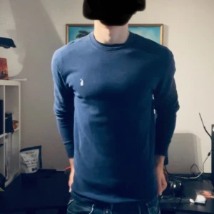 Blå långärmad tröja från Ralph Lauren - Snygg marinblå långärmad tröja från Ralph Lauren i 100% bomull. Klassisk passform med rund halsringning och diskret broderad logga på bröstet. Perfekt för dig som gillar stilrena och tidlösa plagg.