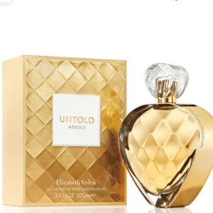 Elizabeth Arden Untold Absolu Parfym - Lyxig parfym från Elizabeth Arden, Untold Absolu, i en elegant guldig flaska med diamantmönster och transparent kristalliknande kork. Flaskan rymmer 100 ml och har en exklusiv känsla med sin hjärtformade design och glänsande yta.(har använts två gånger bara)