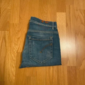 Dondup - Snygga dondup jeans i blå tvätt med slitningar. Klassisk femficksmodell med orangea sömmar och detaljer. Jeansen har låg midja och är tillverkade i stretchig bomullsdenim för en bekväm passform.