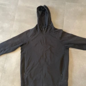 Svart hoodie från SOC med dragkedja - Svart hoodie från SOC i storlek S, med hel dragkedja framtill och två fickor med dragkedja. Tröjan har huva och är tillverkad i mjukt material med meshfoder på insidan. Perfekt för träning eller chill. Klassisk och enkel design.