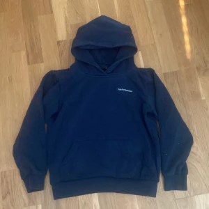 Mörkblå hoodie från Peak Performance - Säljer en mörkblå hoodie från Peak Performance med klassisk logga på bröstet. Tröjan har huva, magficka och ribbade muddar vid ärmslut och nederkant. Perfekt för chill dagar och enkel att matcha med jeans eller mjukisbyxor.