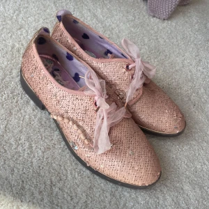  Rosa paljett skor från Irregular Choice - Unika rosa skor från Irregular Choice i London med glittriga paljetter (som är reversable till silver) och andra detaljer. Köpta för nästan 10 år sedan så limited edition på den enda affären som finns. Endast använda ett fåtal gånger.  Perfekt för dig som älskar att sticka ut med färg och glitter.