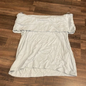 Ljusblå offshoulder tubtopp - Snygg ljusblå tubtopp med offshoulder-design och bred volang upptill. Toppen har en mjuk och stretchig känsla, perfekt för att skapa en chill och trendig look. Axelbandslös och enkel att matcha med dina favoritjeans eller kjol.