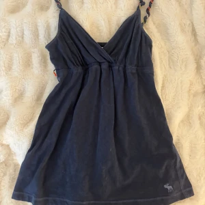 Abercrombie babydoll topp - Vintage abercrombie babydoll topp i stl XS, den är i marinblå med en fin rosett runt midjan. Banden är snyrrade med fina färger. Är öppen för prisförslag ❣️ fattas midjebandet 