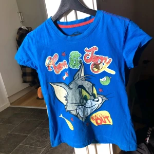 Tom & Jerry 2000-tal - Detta är en unik Tom & Jerry tröja i en fin blå färg ifrån 2000 talet. Tröjan är i storlek 36 ( Xs ) men är stor i storleken så passar även 38 ( S ).  Då tröjan är gammal så är den sliten på framsidan men den har fått kärlek.  Skriv om du har några frågor