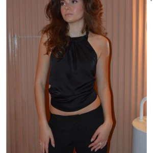 Topp från design by si - Säljer en svart halterneck topp i satin som är ifrån Design By Si. Är i storlek XS/S. Säljer då den är förorten för mig, toppen är aldrig använd och har prislappen kvar. Pris kan diskuteras💕✨