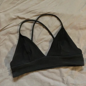 Svart bikini topp - Säljer en svart ribbad bikini topp med smala axelband som korsas i ryggen. 
