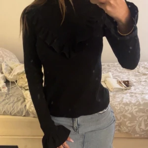 Svart långärmad tröja med volang - Säljer en svart långärmad tröja med hög hals och volangdetalj framtill från SHEIN i storlek xs.