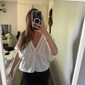 Vit blus ifrån Zara  - En luftig vit blus med v-ringning och spetsdetaljer.