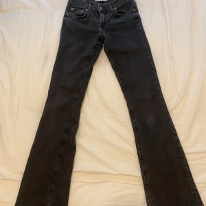 Svarta bootcut jeans från Zara - Säljer ett par svarta bootcut jeans från Zara med klassisk femficksdesign och knappgylf. Jeansen har hög midja och raka ben som slutar i en lätt utsvängd bootcut. Perfekta till sneakers eller boots.