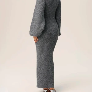 Grå ribbstickad långklänning med knappar - Säljer en snygg grå ribbstickad långklänning med v-ringning och stora ballongärmar från Adoore. Klänningen har knappar hela vägen framtill och är figurnära i modellen. Använd endast en gång.