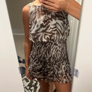 Brun och vit zebra-mönstrad kortklänning - Säljer en söt kortklänning med zebramönster i brunt och vitt. 
