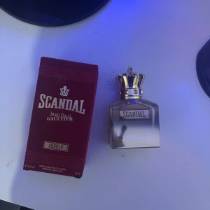 Scandal Absolu herrparfym från Jean Paul Gaultier - Lyxig herrparfym Scandal Absolu från Jean Paul Gaultier. Flaskan är fyrkantig med en silvrig finish och en unik kronformad kork. Förpackningen är vinröd med guldiga detaljer. Perfekt för dig som gillar exklusiva dofter.