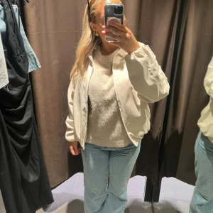 Beige bomberjacka - Säljer en beige bomberjacka med klassisk passform och dragkedja framtill. Jackan har långa ärmar och en enkel, stilren design som passar till många outfits. Perfekt för dig som vill ha en lätt och snygg jacka till vardags.