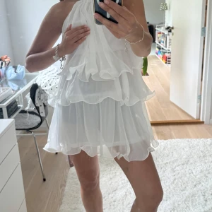 Vit volangklänning - Supersöt vit volangklänning. Tyvärr lite genomskinlig så man kan behöva en vit bandeu under. Därav jag håller handen som jag gör på bilderna. Passar S/M. Den är även lite skimmrig i tyget.