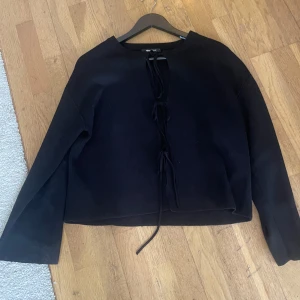 Svart croppad tröja med knyt från Gina Tricot - Snygg svart croppad tröja från Gina Tricot. Då den används en gång och inte kommer till användning. Den är i bra skick och priset kan diskuteras.💗