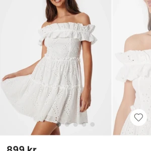 Vit offshoulder klänning med volang och broderade detaljer - Superfin vit offshoulder klänning med volang upptill och broderade hål över hela tyget. Klänningen har en kort, utsvängd kjol och är ärmlös. Perfekt för sommarens alla tillfällen!