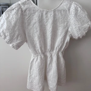 Vit broderad klänning med puffärm - Superfin vit klänning från Gina Tricot med broderade detaljer och puffiga korta ärmar. Klänningen har öppen rygg med knytband och markerad midja. Perfekt för sommarens alla tillfällen! 