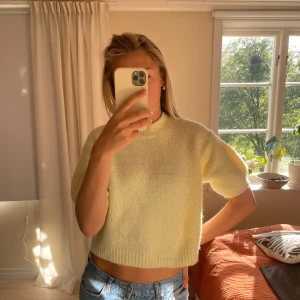 Gul  stickad tröja - Säljer en ljusgul stickad tröja med korta ärmar och rund hals. Tröjan har en mjuk och fluffig känsla, perfekt för vår och sommar. Passar snyggt till jeans eller kjol.