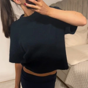 Marinblå stickad tröja - Säljer en marinblå stickad tröja med korta ärmar och rund halsringning. Perfekt för en avslappnad och trendig look. Passar bra till både jeans och kjol.