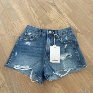 Jeansshorts från Pull&Bear - Blå jeansshorts från Pull&Bear med slitna detaljer. Normal i storlek. 