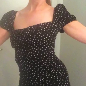 Svart prickig klänning från Missguided - Säljer en svart klänning med vita prickar från Missguided. Klänningen har korta ärmar och en smickrande passform. Perfekt för en stilren look!