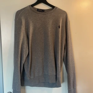 Grå tröja från Polo Ralph Lauren - Säljer en stilren grå tröja från Polo Ralph Lauren Tröjan har inga problem säljer den för den är för stor. En snygg tröja till sommarn ‼️priset är inte hugget i sten‼️