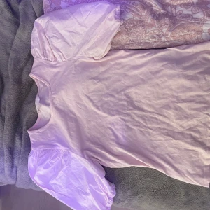 Ljusrosa t-shirt med puffärmar - Säljer en söt ljusrosa t-shirt med puffiga kortärmar. Perfekt för en avslappnad och stilren look. T-shirten har en rund halsringning och är gjord i ett mjukt material.