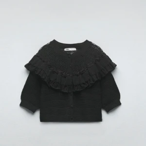 Svart kofta med volang från Zara - Säljer en snygg svart kofta från Zara med vackra volangdetaljer och spetsmönster. Tröjan är aldrig använd och inga skador eller fläckar finns