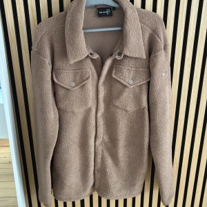 Beige fleecejacka från Pelle P - Säljer en mysig beige fleecejacka från Pelle P. Jackan har långa ärmar och knappar framtill samt två bröstfickor med knapp. Perfekt för sommarkvällar!
