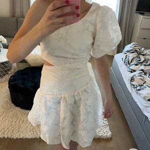 Studentklänning - Säljer denna superfina vita enaxlade klänning från SHEIN som är perfekt både till studenten eller andra tillställningar. Den är i storlek xs och aldrig använd med lappen kvar, utan endast testad eftersom jag råkade köpa två i samma storlek. Den är sann till storleken och passar bra på mig som är 165 men även andra längder beroende på hur man vill att den ska sitta och hur kort den ska vara. Den är köpt för 289 kr och slutsåld i denna storleken. Tveka inte att höra av er vid frågor/prisförslag