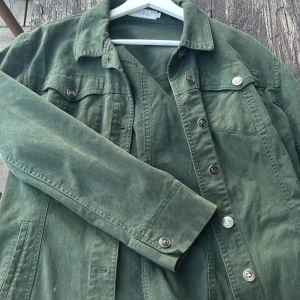 Grön jeansjacka - Snygg grön jeansjacka med knappar framtill och klassisk krage. Jackan har långa ärmar och två bröstfickor med knappstängning. Perfekt för en avslappnad stil. Den är i storlek 40 men liten i storlek skulle jag säga skriv för referens bild