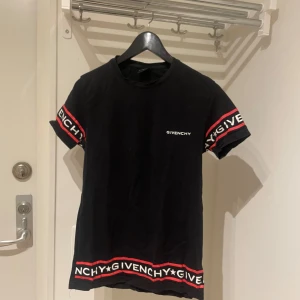 Svart t-shirt från Givenchy Herr S - Snygg svart t-shirt från Givenchy med korta ärmar och röd-vit logotypdetalj på ärmar och nederkant. Perfekt för en stilren look. Storlek s men kan även passa xs 