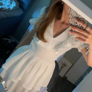 Vit klänning från Gina Tricot - Säljer en söt vit klänning från Gina Tricot med volangdetaljer och v-ringning. Klänningen har korta ärmar och en smickrande passform. Perfekt för skolavslutningen! Endast använd vid 2 tillfällen