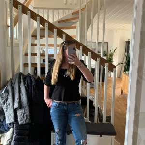 Svart blus med smockdetaljer - Säljer en stilren svart blus med smockdetaljer och trekvartsärmar. Blusen har en vacker fyrkantig urringning och en lätt volang vid nederkanten. Perfekt för en chic look!