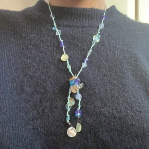 Färgglatt halsband med pärlor - Unikt halsband med en mix av blå, lila och turkosa pärlor. Halsbandet har en dekorativ design med hängande detaljer och en justerbar kedja i metall. Perfekt för att ge en färgklick till din outfit. Aldrig använt🤍