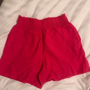 Rosa, line shorts  - Säljer rosa line shorts med bekväm resårmidja. Perfekta för varma sommardagar. De är enkla och stilrena, vilket gör dem lätta att matcha med olika toppar.