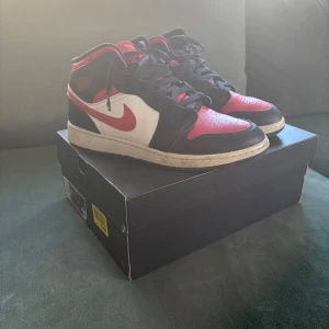 Nike Air Jordans i svart, röd och vit - Säljer ett par klassiska Nike Air Jordans i svart, röd och vit. Skorna har en ikonisk design med snörning och rund tå. Perfekta för sneakerheads som vill ha en tidlös stil.