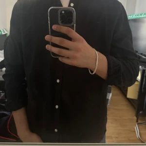 Mörkblå linneskjorta - Snygg svart skjorta i linne med knappar framtill. Perfekt för en stilren look. Skjortan har långa ärmar och en klassisk krage. Och priset kan diskuteras vid snabb affär