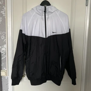 Svart och vit vindjacka från Nike - Säljer en stilren svart och vit vindjacka från Nike. Storlek L 
