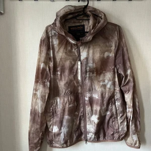 Mönstrad jacka från Woolrich - Säljer en cool mönstrad jacka från Woolrich i jordnära toner. Jackan har en dragkedja framtill och en praktisk huva. Perfekt för en avslappnad stil.