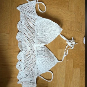 Vit stickad topp från SHEIN - Snygg vit stickad topp från SHEIN med knytband i nacken och ryggen. Den har en vacker virkad design med volangdetaljer längs kanten. Perfekt för en dag på stranden eller vid poolen.