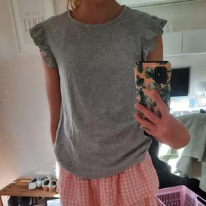Grå topp med volang - Säljer min gråa topp med volang från POMPdeLUX pga att den inte kommer till användning. Den har volang runt ärmarna och guldglittriga ränder. Kan matchas till exempelvis byxor i samma färg. Använd ett fåtal gånger. Köparen står för frakten🥰
