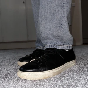 Svarta sneakers  - Storlek 45, från Jack and Jones. Imitationsläder, på sidorna och på framsidan är det lite skavt. Skorna är endast avtorkade.